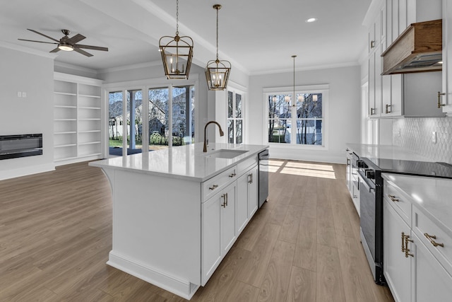 kitchen with pendant lighting, sink, white cabinetry, an island with sink, and custom range hood