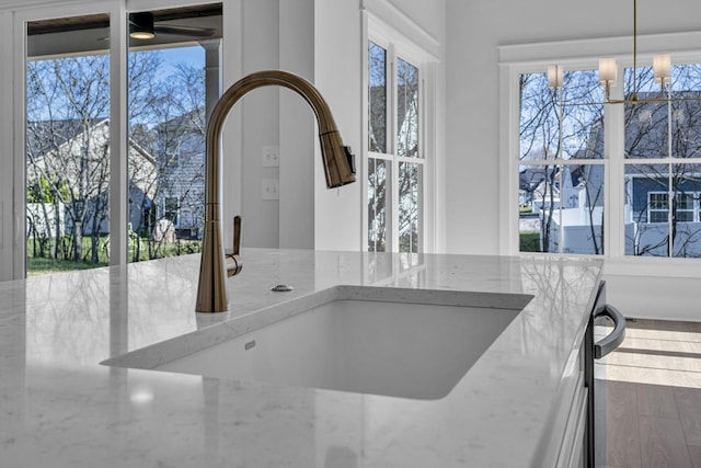 interior details featuring light stone counters, decorative light fixtures, a chandelier, and sink