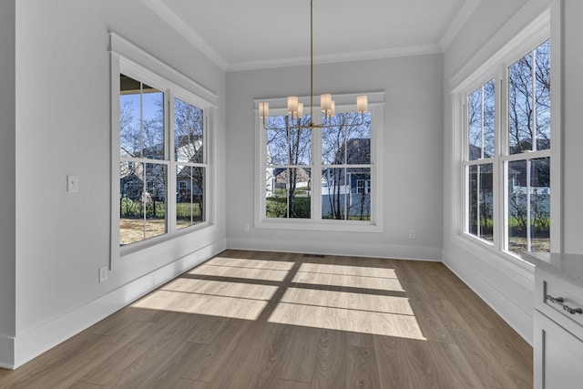 unfurnished dining area with hardwood / wood-style flooring, ornamental molding, and a chandelier