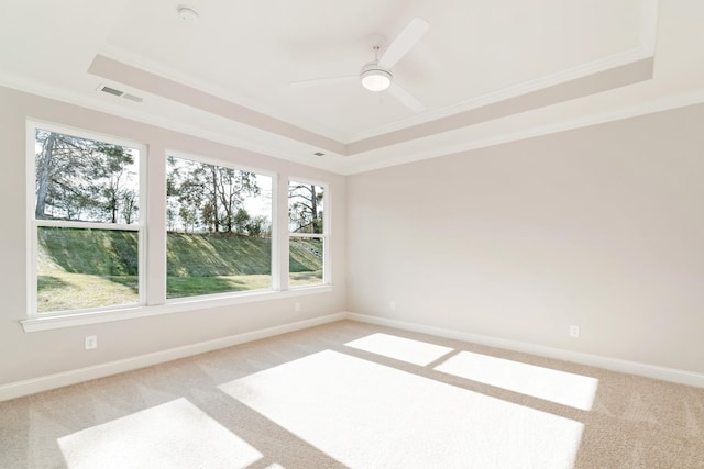 spare room with light carpet, baseboards, visible vents, a raised ceiling, and crown molding