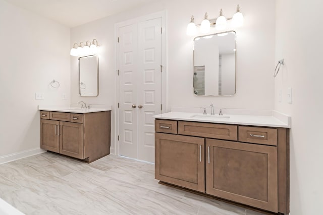 bathroom featuring marble finish floor, two vanities, a sink, and baseboards