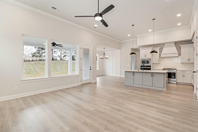 kitchen featuring custom range hood, a kitchen island with sink, stainless steel appliances, light countertops, and pendant lighting