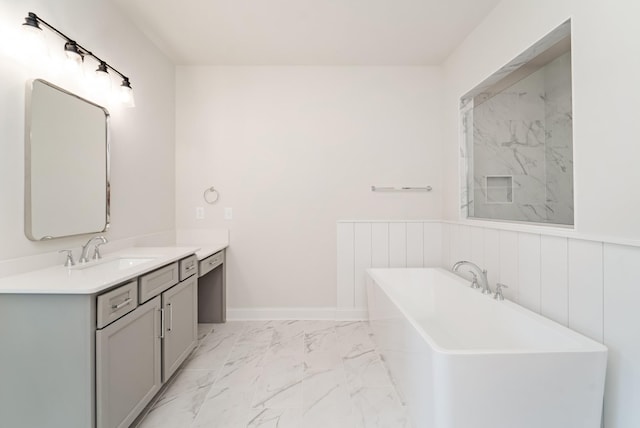 bathroom featuring marble finish floor, a freestanding tub, vanity, and baseboards