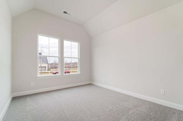 spare room with lofted ceiling, carpet floors, visible vents, and baseboards