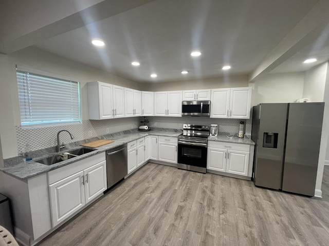 kitchen with sink, white cabinetry, stainless steel appliances, light hardwood / wood-style floors, and light stone countertops