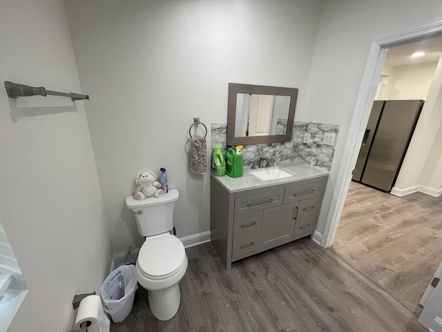 bathroom with wood-type flooring, toilet, backsplash, and vanity