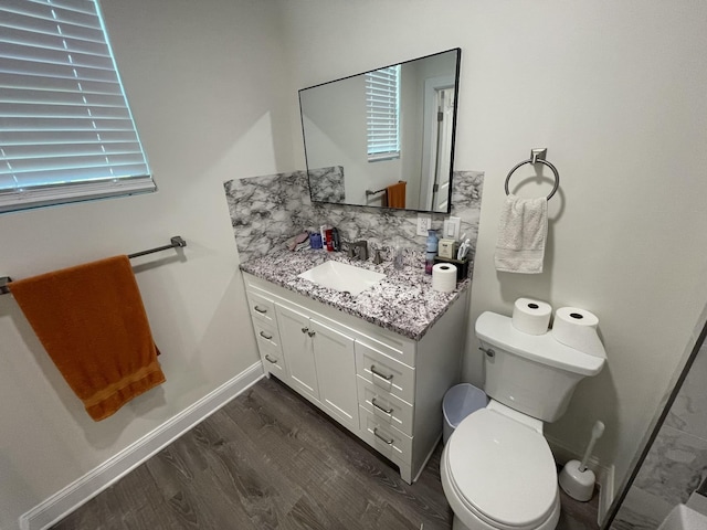 bathroom featuring wood-type flooring, toilet, backsplash, and vanity