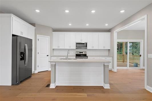 kitchen featuring white cabinetry, appliances with stainless steel finishes, sink, and a kitchen island with sink