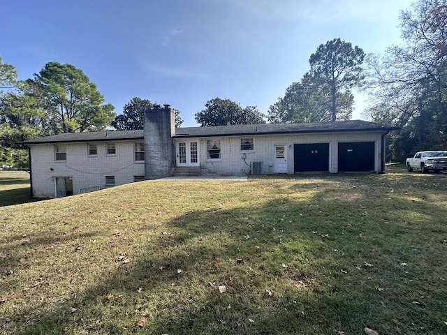 back of house with a garage, a yard, and cooling unit