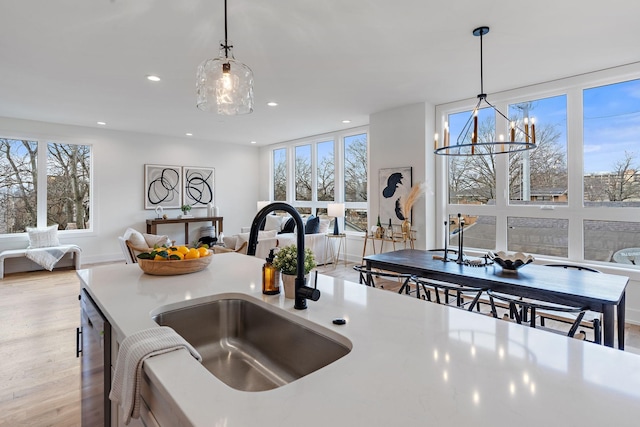 kitchen with sink, an inviting chandelier, dishwasher, pendant lighting, and light hardwood / wood-style floors