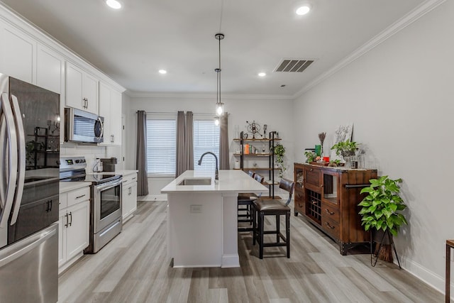 kitchen with sink, stainless steel appliances, white cabinets, a center island with sink, and decorative light fixtures