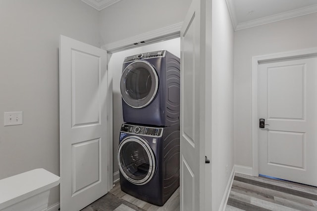 washroom featuring stacked washing maching and dryer, ornamental molding, and light wood-type flooring