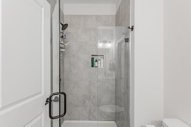 bathroom with a shower with shower door and toilet