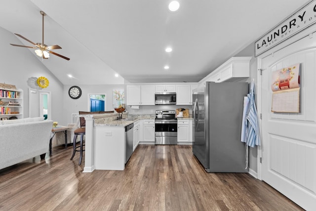 kitchen featuring white cabinetry, light stone counters, kitchen peninsula, stainless steel appliances, and dark wood-type flooring