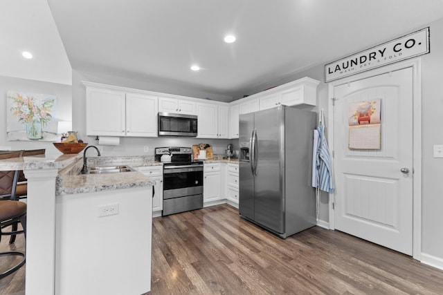 kitchen with sink, a breakfast bar, white cabinetry, stainless steel appliances, and kitchen peninsula