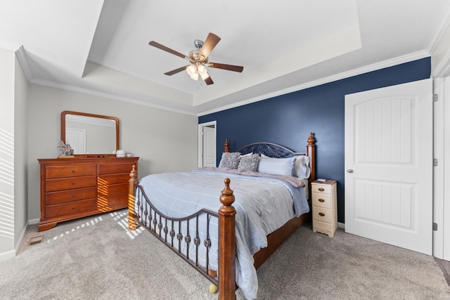 bedroom featuring ceiling fan, light colored carpet, ornamental molding, and a tray ceiling