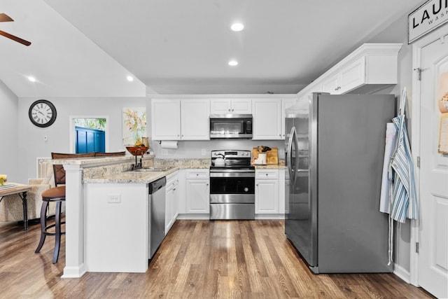 kitchen featuring white cabinetry, appliances with stainless steel finishes, kitchen peninsula, and a breakfast bar area