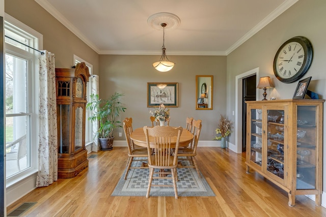 dining room with ornamental molding, a healthy amount of sunlight, and light wood-type flooring