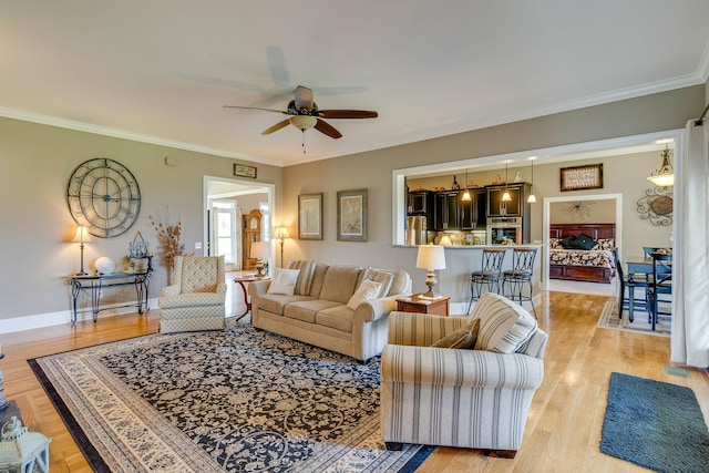 living room with ornamental molding, light hardwood / wood-style floors, and ceiling fan