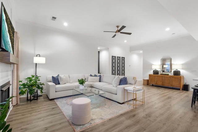 living room with ornamental molding, ceiling fan, and light hardwood / wood-style flooring