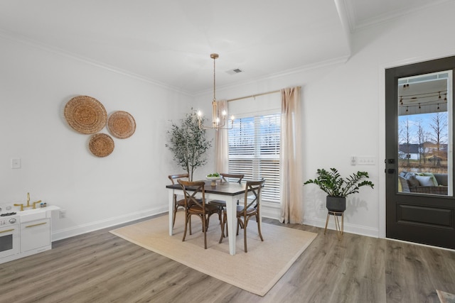 dining space with crown molding, a notable chandelier, and hardwood / wood-style flooring