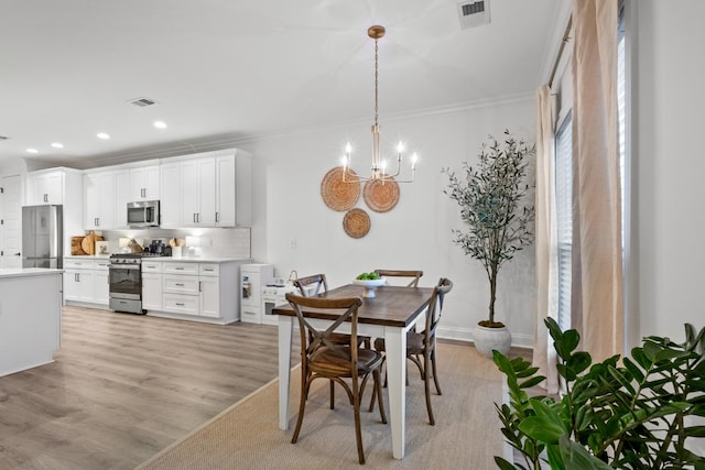 dining space with a notable chandelier, crown molding, and light wood-type flooring