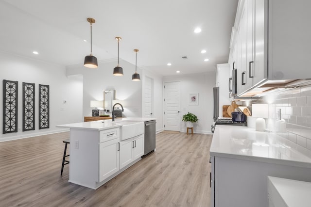 kitchen featuring pendant lighting, sink, appliances with stainless steel finishes, a kitchen island with sink, and white cabinets