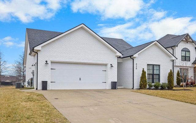 view of front of house featuring a garage, a front lawn, and central air condition unit