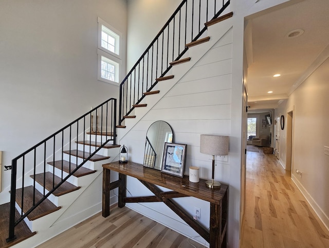 stairway with a healthy amount of sunlight, hardwood / wood-style floors, and a high ceiling