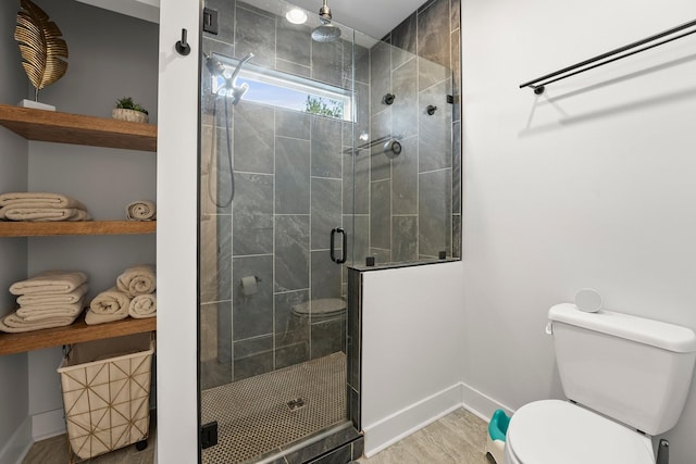 bathroom with toilet, a shower with shower door, and hardwood / wood-style floors