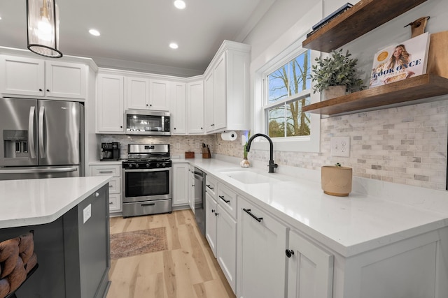 kitchen with appliances with stainless steel finishes, sink, pendant lighting, and white cabinets