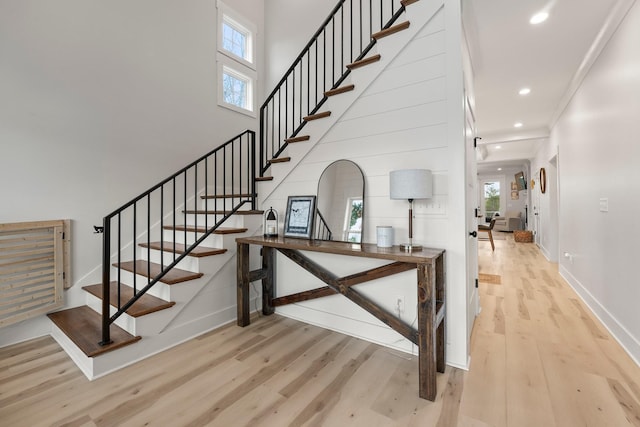 stairs featuring hardwood / wood-style flooring, a healthy amount of sunlight, and a towering ceiling