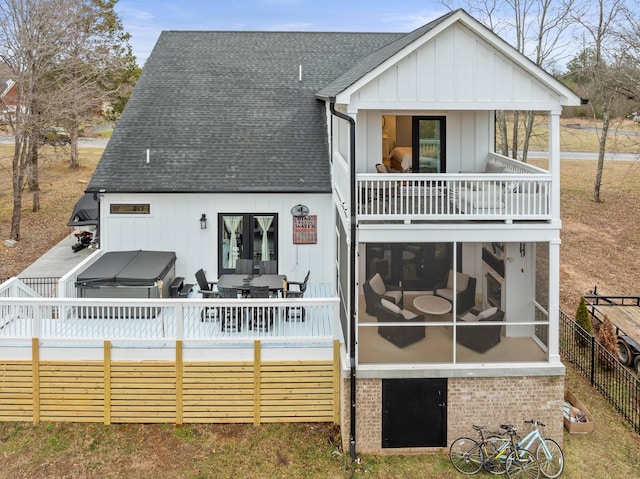 rear view of house with a sunroom, a balcony, and a covered hot tub