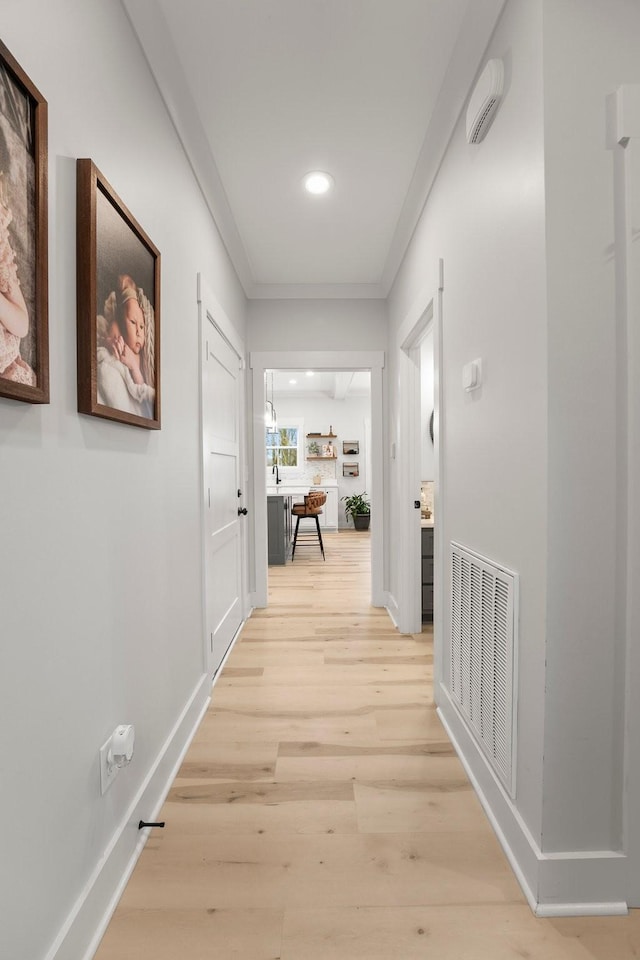 corridor featuring crown molding, sink, and light wood-type flooring