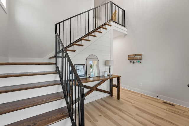 stairway with hardwood / wood-style flooring and a towering ceiling