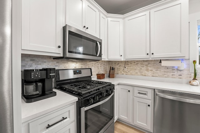 kitchen with white cabinetry, stainless steel appliances, tasteful backsplash, and light wood-type flooring