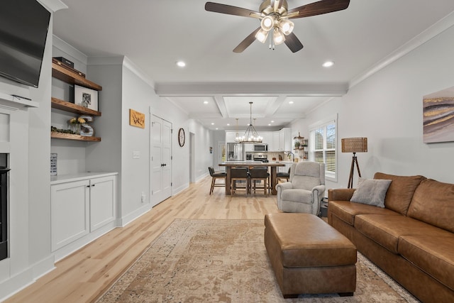 living room featuring ceiling fan with notable chandelier, beamed ceiling, sink, crown molding, and light wood-type flooring