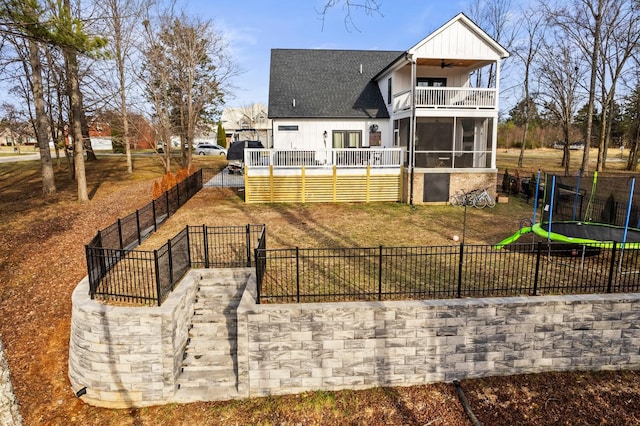 rear view of property with a trampoline, a sunroom, and a balcony