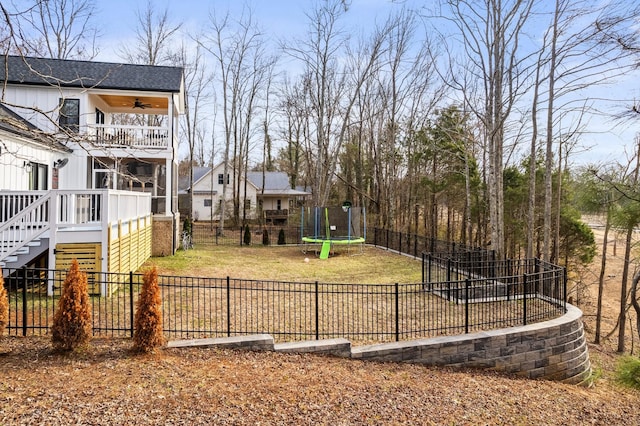 view of yard featuring a balcony, a trampoline, and ceiling fan