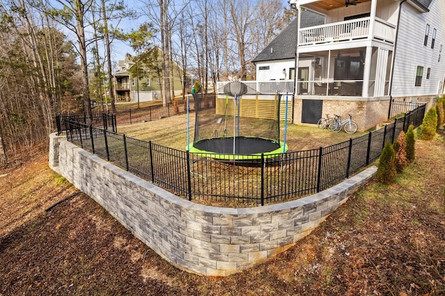 view of yard with ceiling fan, a trampoline, and a sunroom