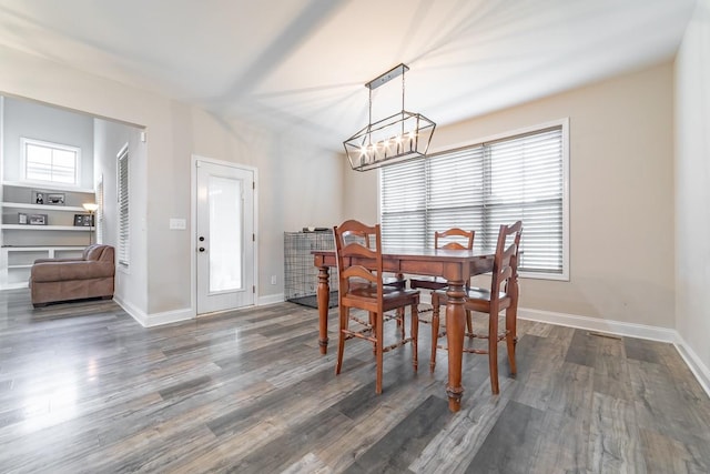 dining area featuring dark hardwood / wood-style flooring, a wealth of natural light, and an inviting chandelier