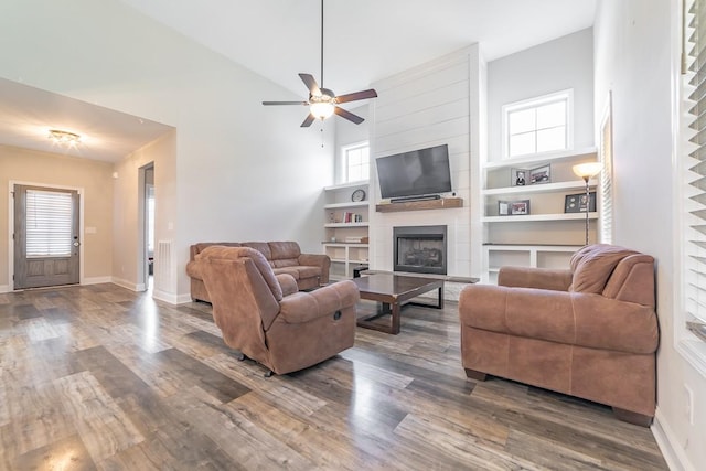 living room with dark hardwood / wood-style flooring, a healthy amount of sunlight, a fireplace, and a towering ceiling