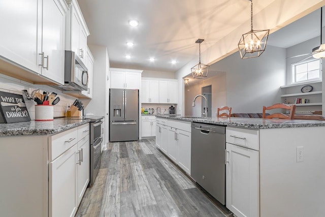 kitchen featuring stainless steel appliances, white cabinetry, sink, and decorative light fixtures