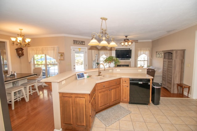 kitchen with a large island with sink, black dishwasher, sink, and decorative light fixtures