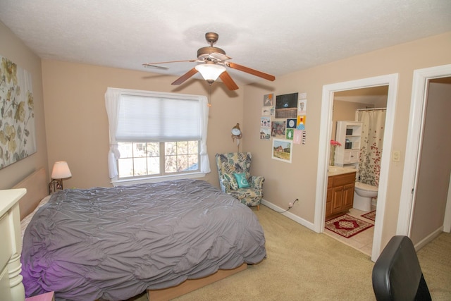 bedroom with connected bathroom, light colored carpet, and ceiling fan