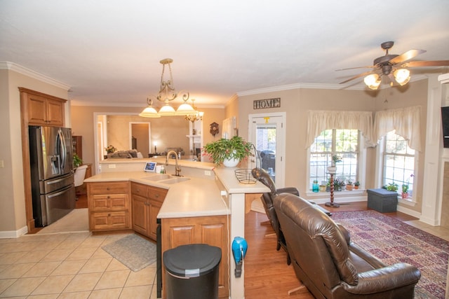 kitchen with pendant lighting, stainless steel fridge with ice dispenser, crown molding, and sink