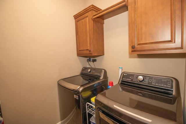 clothes washing area with cabinets and washer and dryer