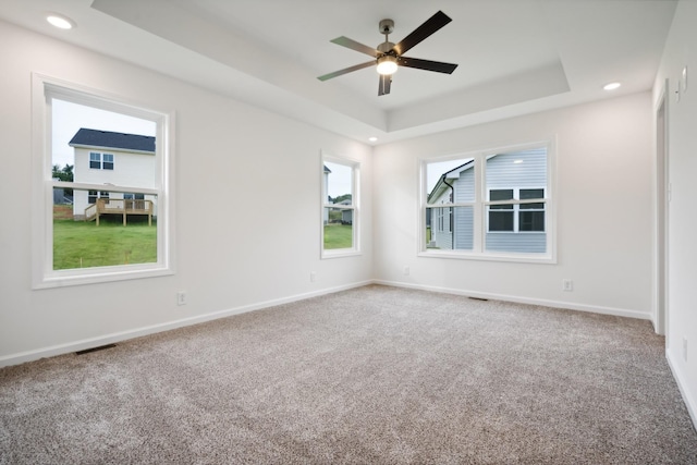 empty room featuring carpet floors, baseboards, visible vents, and a raised ceiling