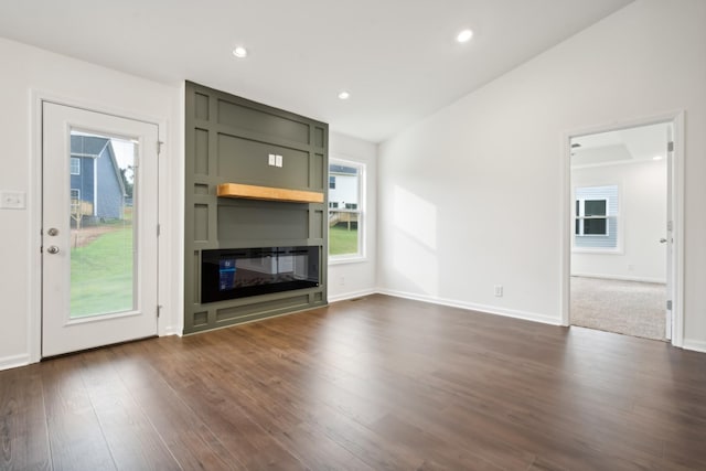 unfurnished living room featuring a large fireplace, plenty of natural light, dark wood-style floors, and recessed lighting