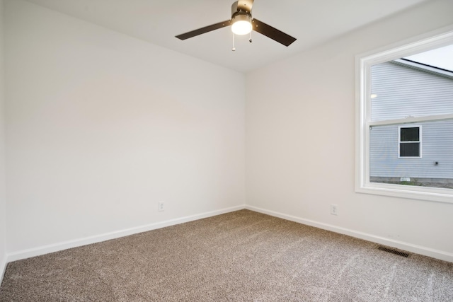 carpeted spare room featuring visible vents, baseboards, and a ceiling fan